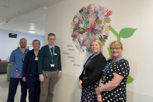 Andrew Murray (Medical Director), Kirsten Cassells (Lead Pharmacist Community Pharmacy, Public Health and Integrated Services and Chair of the Area Clinical Forum) and Lynda Bennie (Head of Clinical Governance), Katie Dickinson (Ward 1 Senior Charge Nurse) and Liam Middleton (Ward 1 Deputy Charge Nurse) are pictured above next to a display designed by the staff and patients within Ward 1 at Forth Valley Royal Hospital.